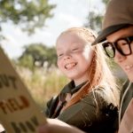 boy and girl looking at book and smiling on summer camp holiday